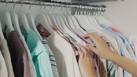 hands of a child, chooses a dress on a coat hanger in the wardrobe