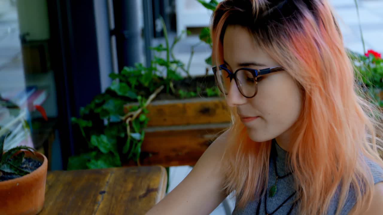 mujer tomando café mientras usa una computadora portátil en un café al aire libre 4k