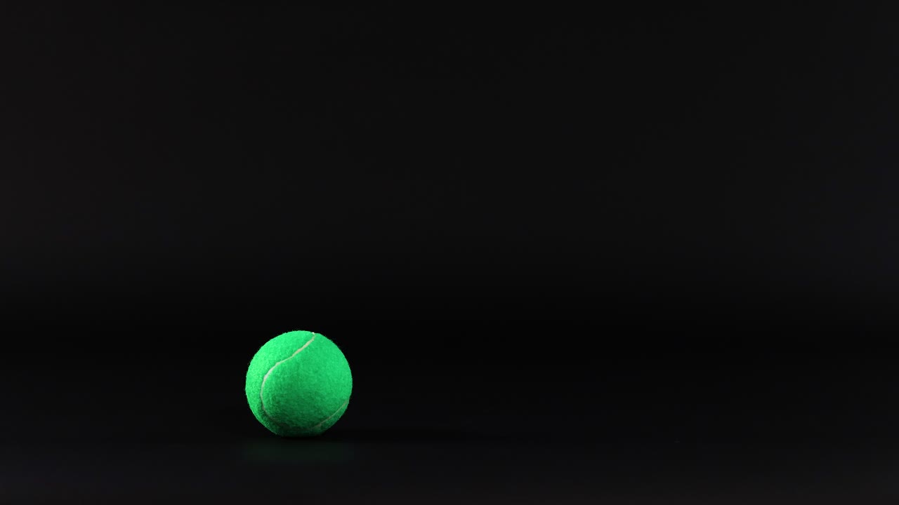 A tennis ball bounces in a dark space