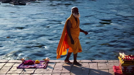 elderly sadhu by a river performing a religious ritual