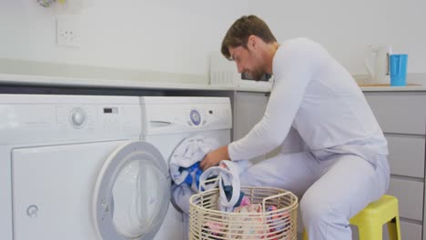 hombre poniendo ropa en la lavadora en casa 4k