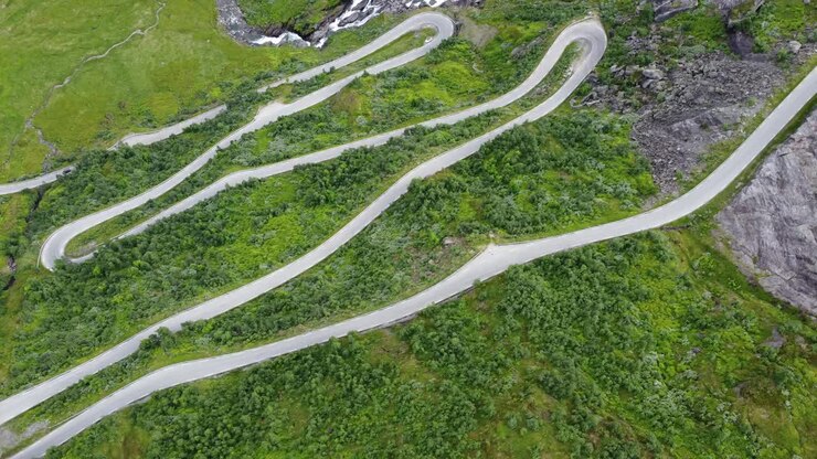 Unique Norwegian winding roads leading to mountain crossing Vikafjell along road rv13 - Top down birdseye aerial looking down at steep hillside with crazy curves