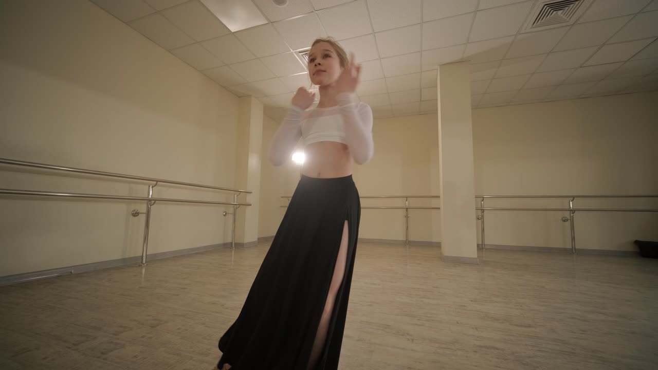 un grupo de jóvenes estudiantes de ballet con ropa de baile negra practicando posiciones en un amplio estudio de ballet con pisos de madera y barras montadas en la pared. expresiones enfocadas y movimientos sincronizados.