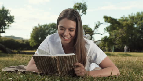 woman reading book lying on lawn