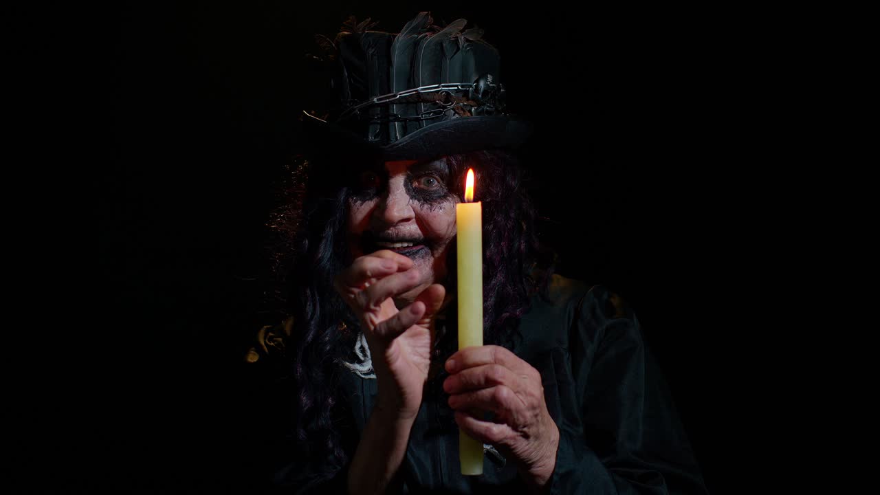 Creepy mature woman grandmother with Halloween stylish witch makeup making voodoo magic rituals