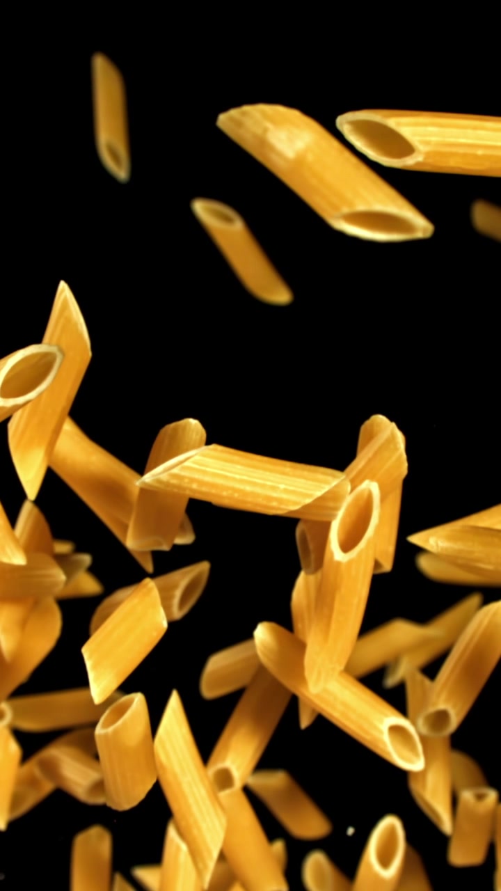 Penne dorate che cadono al rallentatore su uno sfondo nero