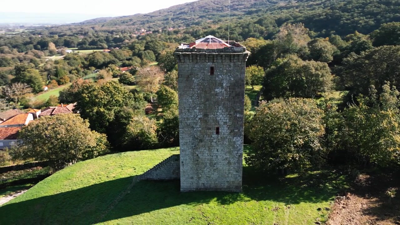 Tårnet A Forxa og gresskledde områder vises blant trær i Porqueira, Galicia, Spania, etablerende luftfoto i sirkel.