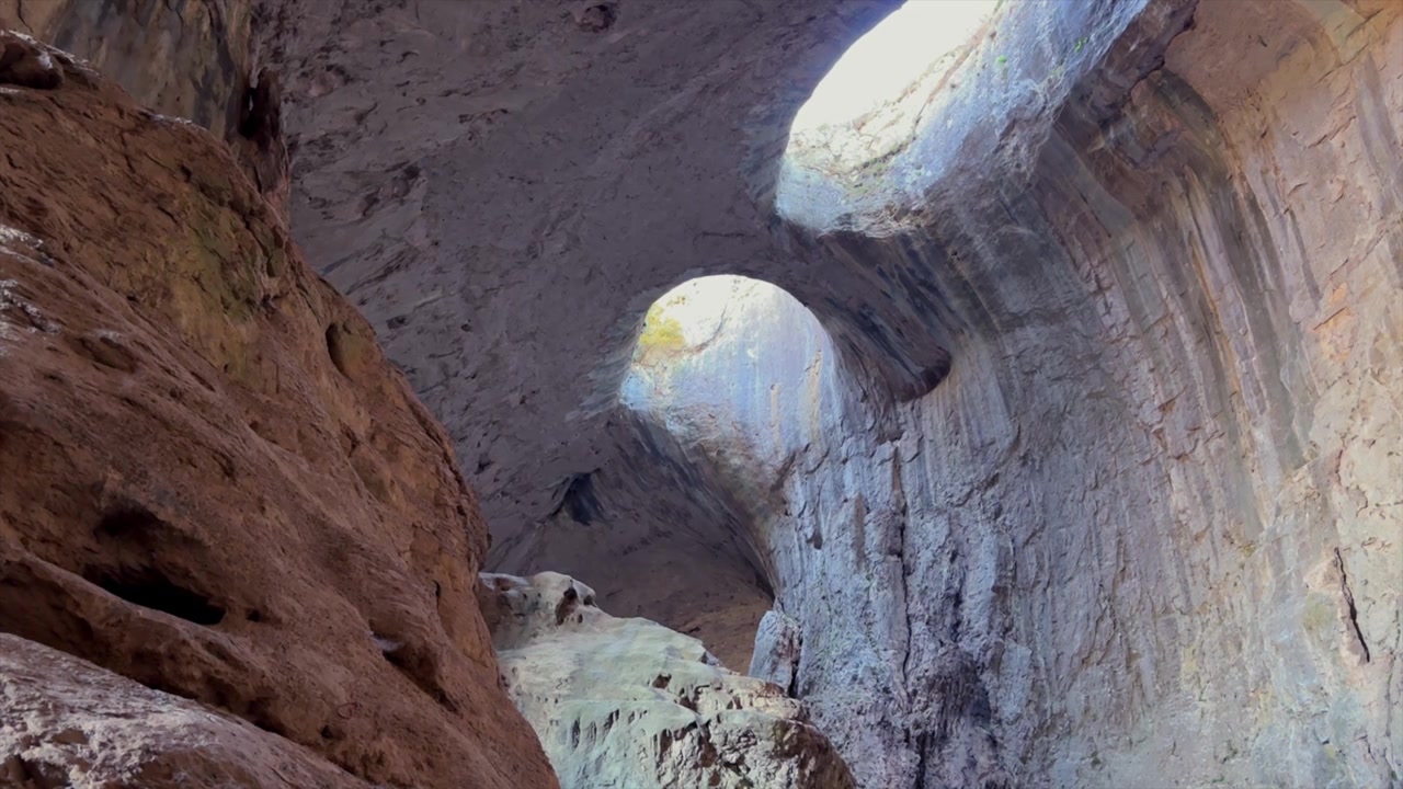 Raios de sol atravessando as famosas formações rochosas conhecidas como Os Olhos de Deus na Caverna Prohodna, um marco natural em Karlukovo, Bulgária