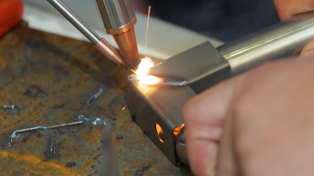 Laser welding machine with hand hold gun. Laser welding is shown in close-up.