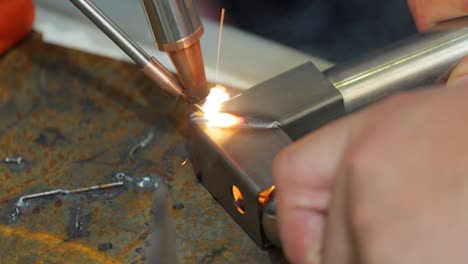 Laser-welding-machine-with-hand-hold-gun.-Laser-welding-is-shown-in-close-up.