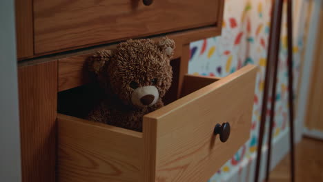 a playful teddy bear interacting with a drawer