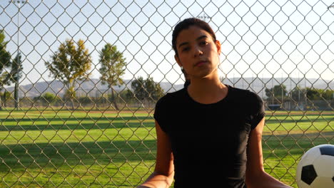 una jugadora de fútbol atleta fuerte y confiada sosteniendo una pelota de fútbol durante un juego deportivo competitivo