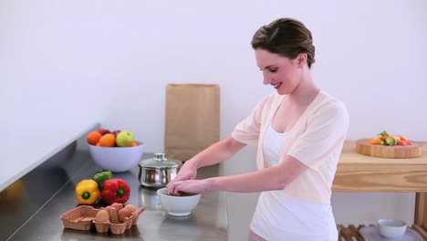 Pretty-model-standing-in-kitchen-preparing-an-omelette