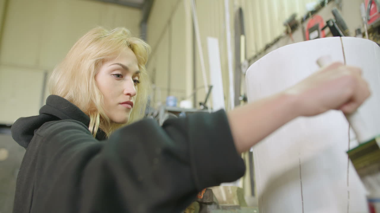 женщина-плотник красит пень в мастерской 1