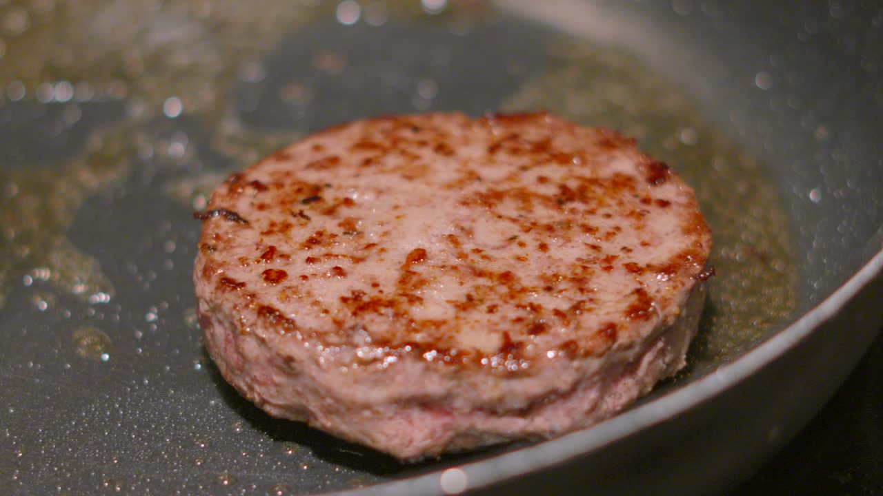 Beef Burger Flipped in Hot Pan with Bubbling Hot Oil. Cooking Meat to Serve with Bun. Slow Motion Clip