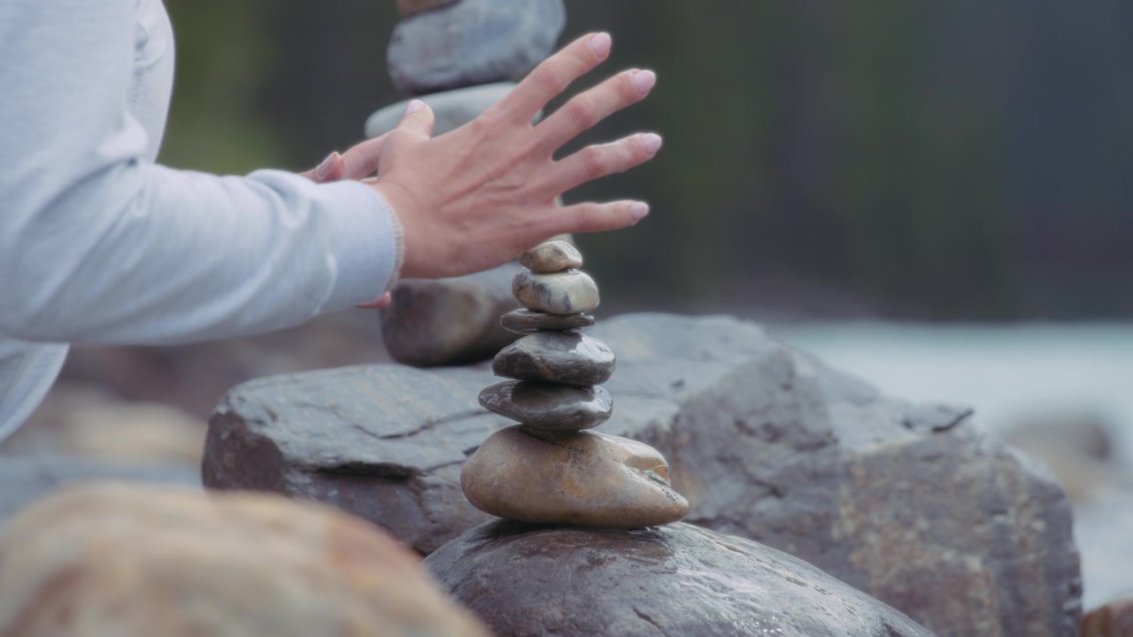 A woman balancing stones near the mountain river