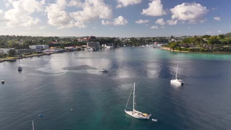 port vila, efate, vanuatu - a coastal tropical city with boats and yachts anchored in the harbor beneath a sky filled with fluffy clouds - aerial drone shot