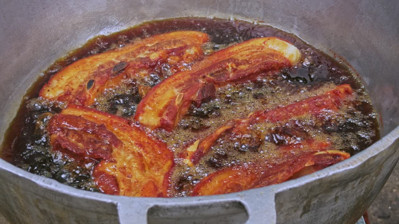 Deep frying chicharron de cerdo in a traditional pot in Santiago, Dominican Republic