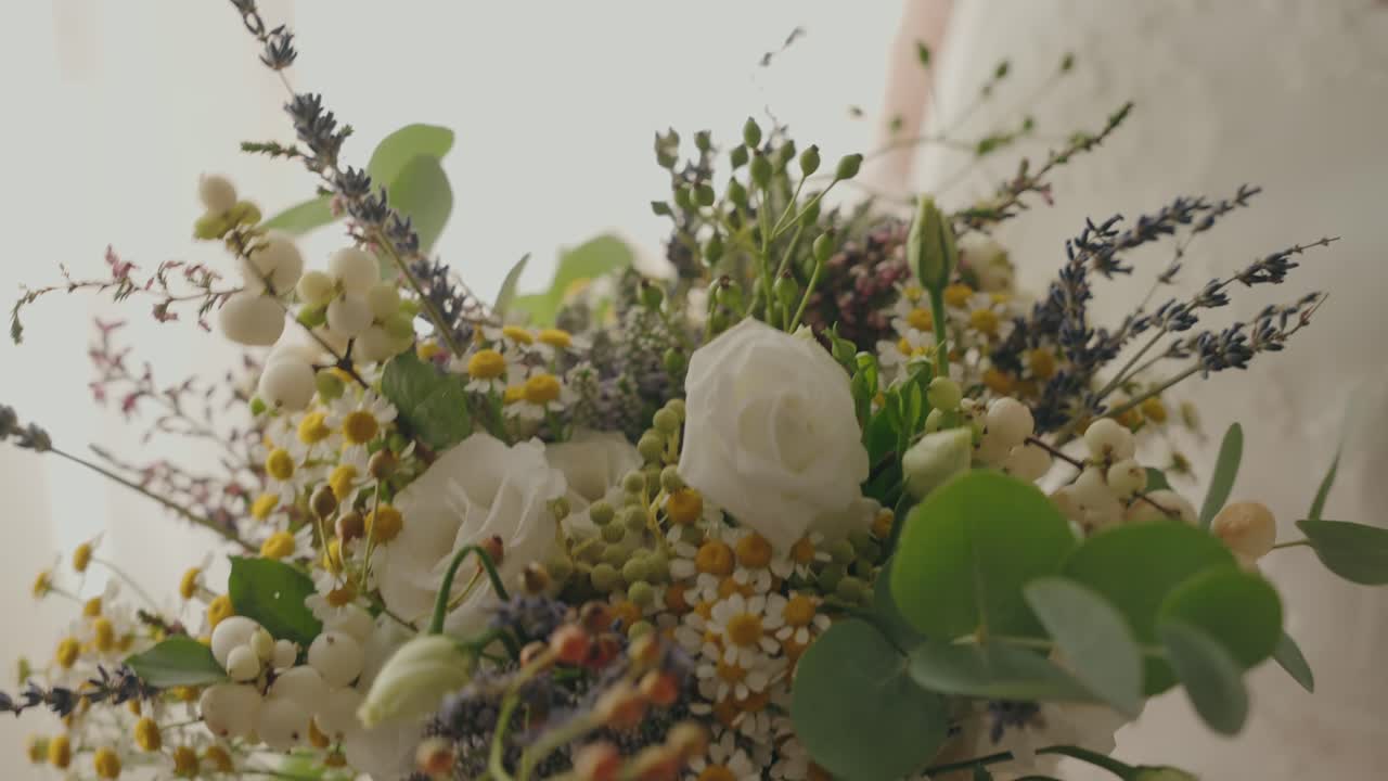 Close up of wedding bouquet with white roses greenery and small flowers