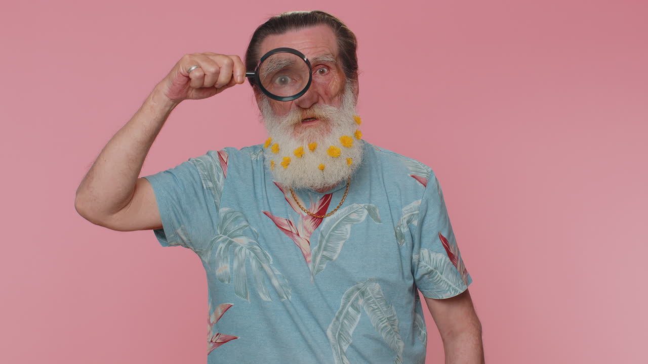 investigador hombre mayor sosteniendo una lupa cerca de la cara, mirando a la cámara con un gran ojo ampliado