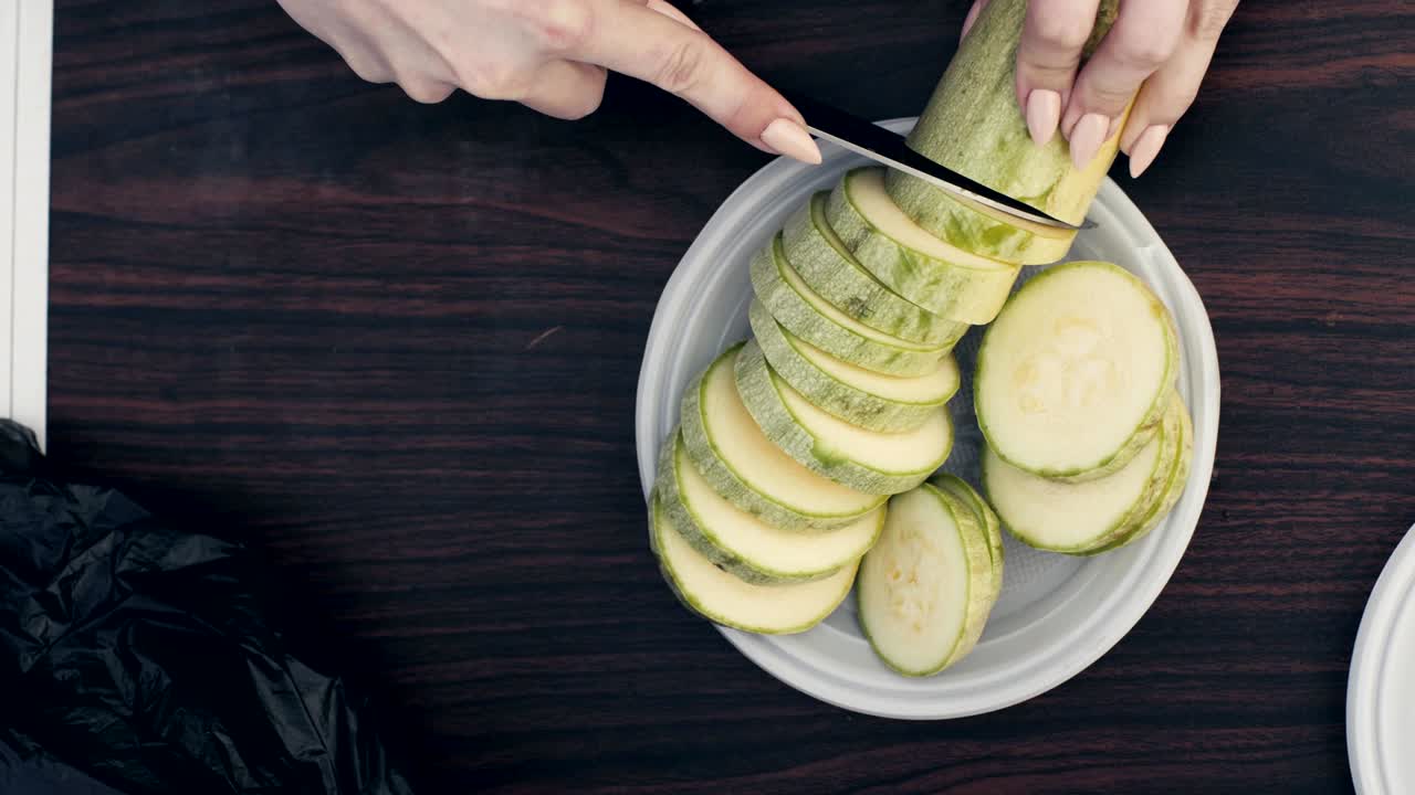 테이블  뷰 에 있는 접시 에 있는 채소 골수 를 칼 으로 자르는 여자 손