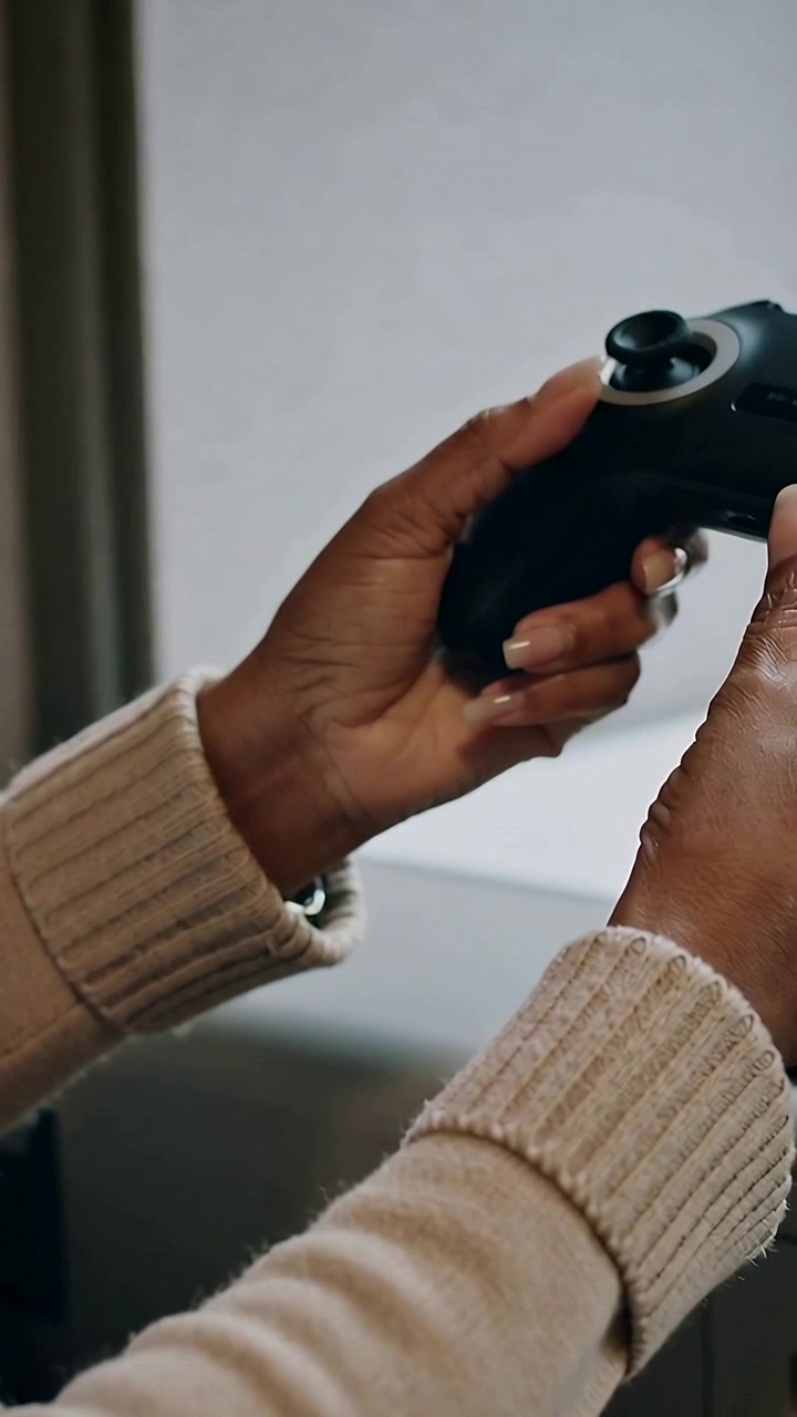 Vertical video: Entering left hand holding pad at desk, other hand readying joystick for play