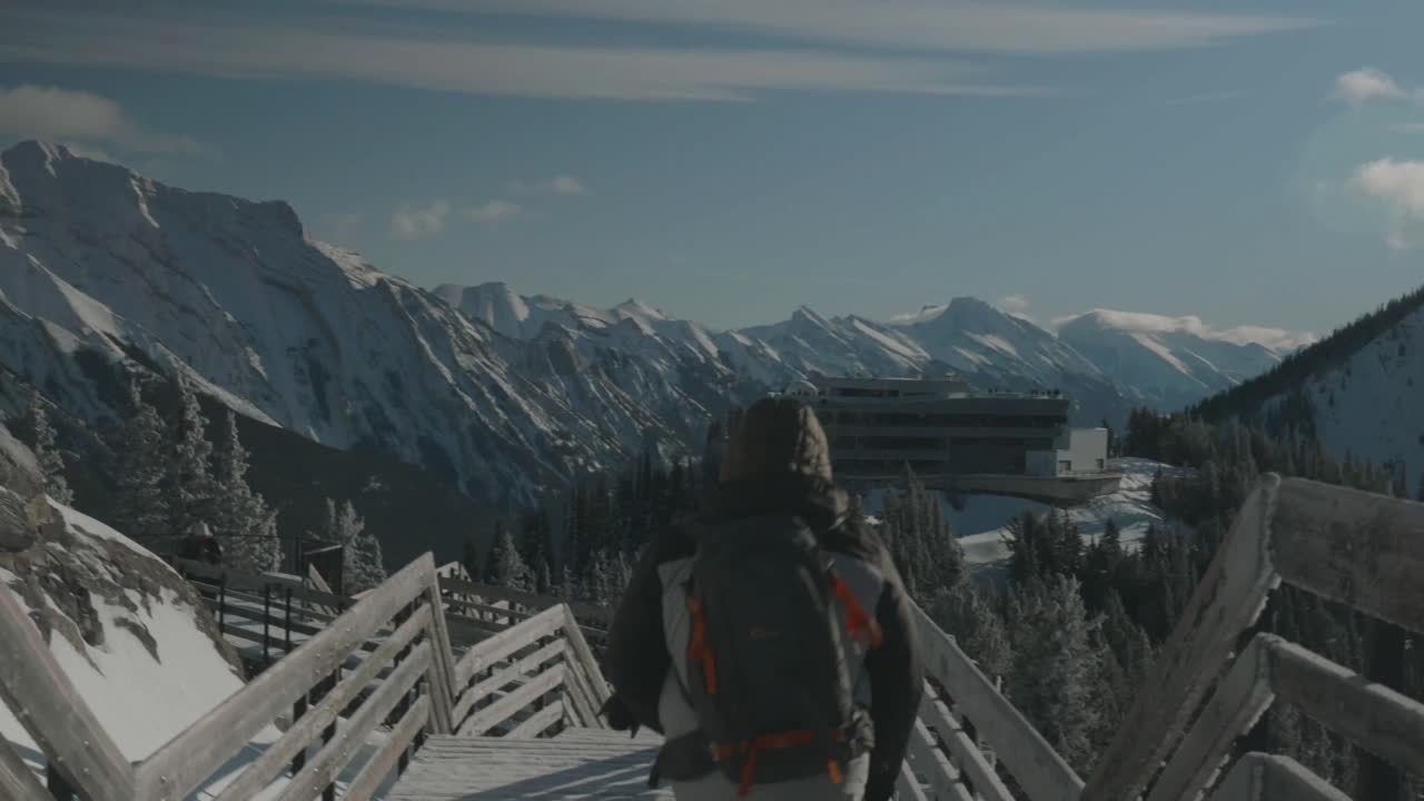 Person Hiking on Snowy Mountain Trail with Resort in Background