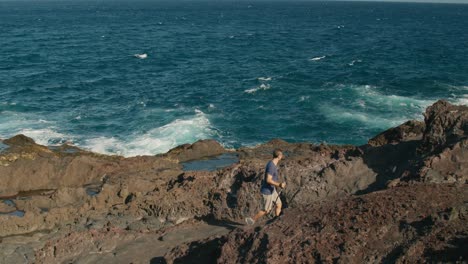 Turista-Masculino-Caminando-Por-La-Orilla-Del-Mar-Volcánico