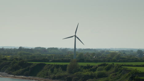 Energetische-Windkraftanlage:-Schnelle-Rotation-In-Der-Nähe-Von-Klippen-Und-Wasser-Auf-Der-Grünen-Wiese-In-Dänemark