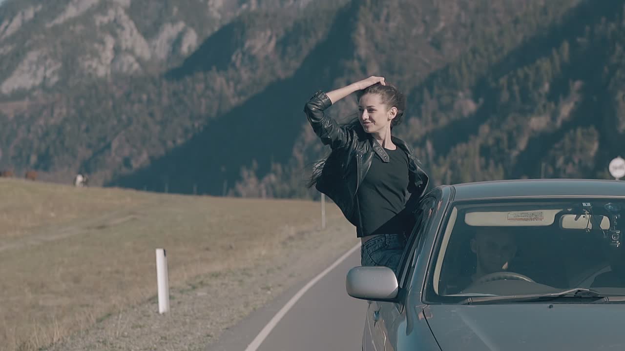 la dama se inclina hacia fuera de la ventana del coche obtiene placer de la velocidad del coche