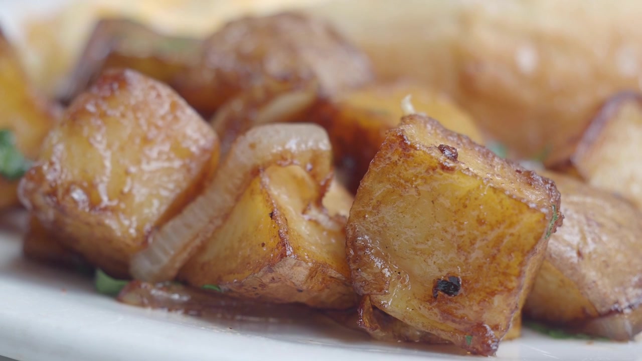 Primo piano di patate arrosto croccanti con cipolle