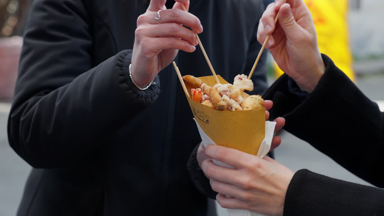 People sharing a tasty fried snack, enjoying a moment together in Genoa, Italy