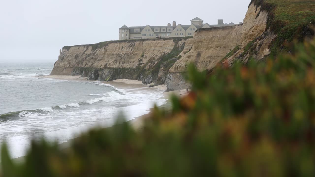 la costa de la bahía de la mitad de la luna - las olas que llegan a la orilla de la playa de manhattan con el hotel ritz-carlton en el acantilado