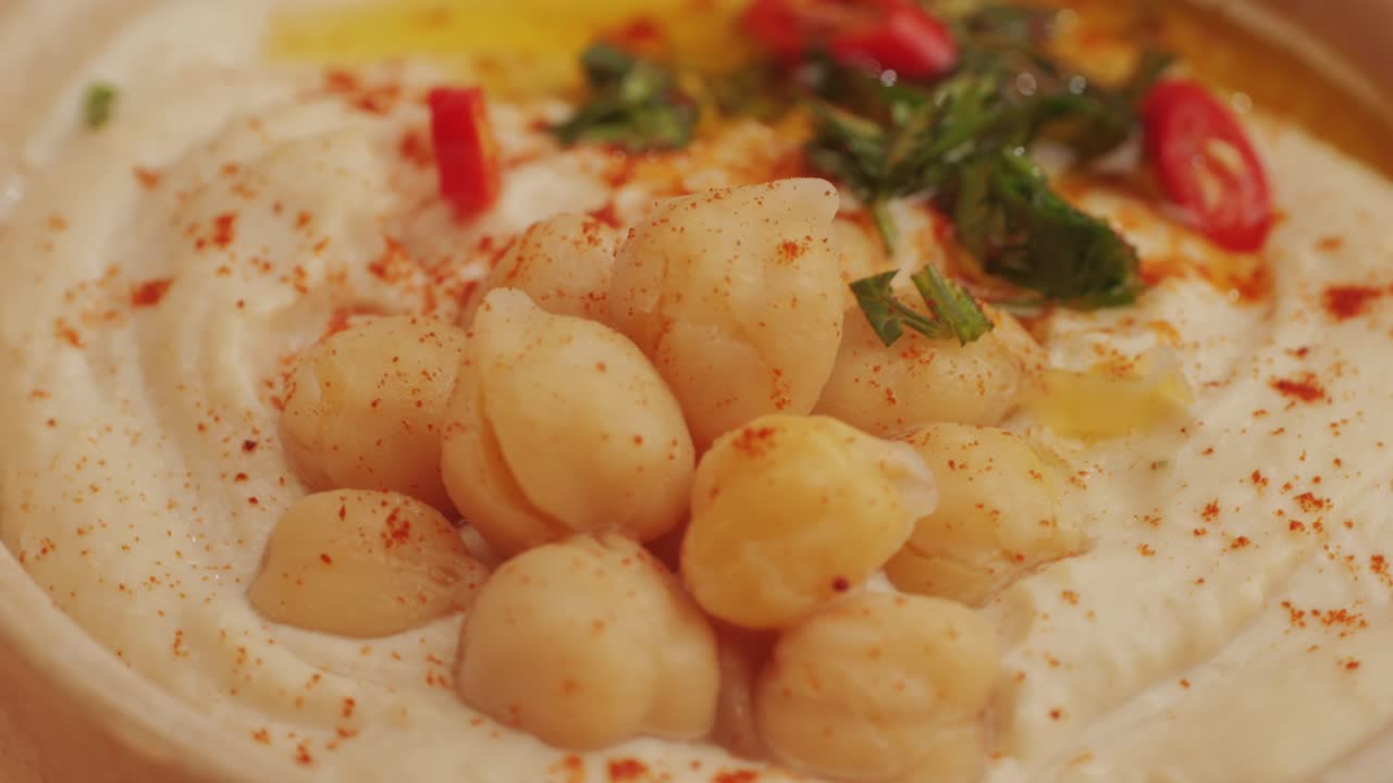 Hummus among fresh vegetables on table close-up. Hummus garnished with chickpeas, olive oil, spices and greens. Hummus or fava, a hearty snack of legumes. Kosher healthy vegan food. Lean, vegetarian dish