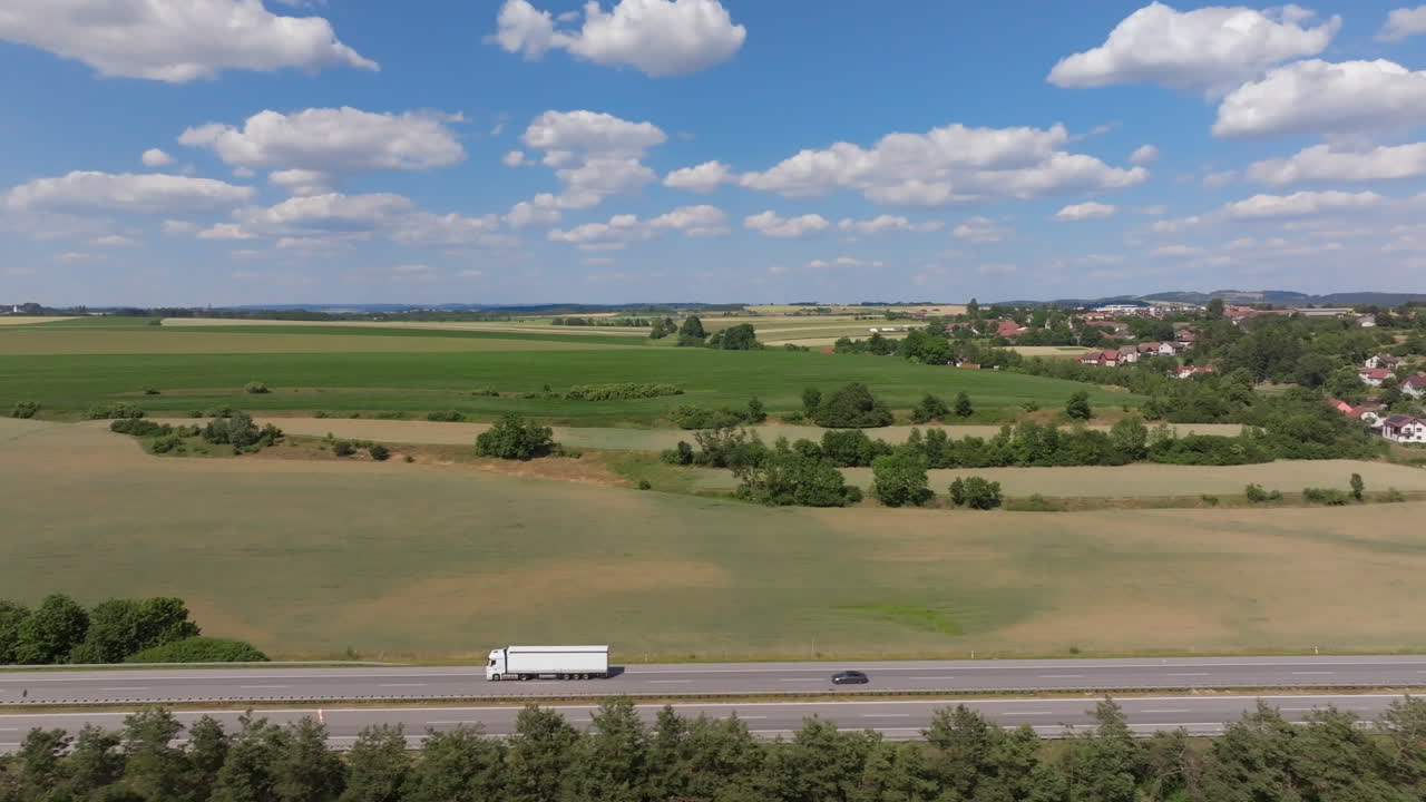 Luftfoto af en lastbil, der kører på en motorvej gennem et naturskønt landskab