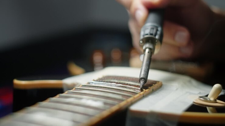 Tecnico riparatore di chitarre che salda il manico della chitarra