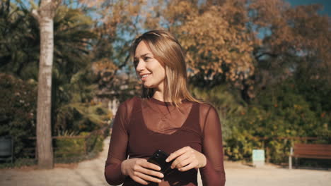 Mujer-Rubia-Mirando-La-Cámara-Sosteniendo-El-Teléfono.