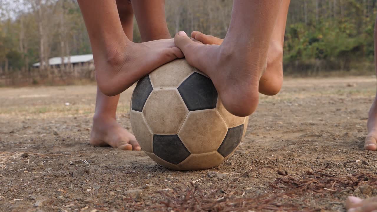 Children playing soccer on a dirt field