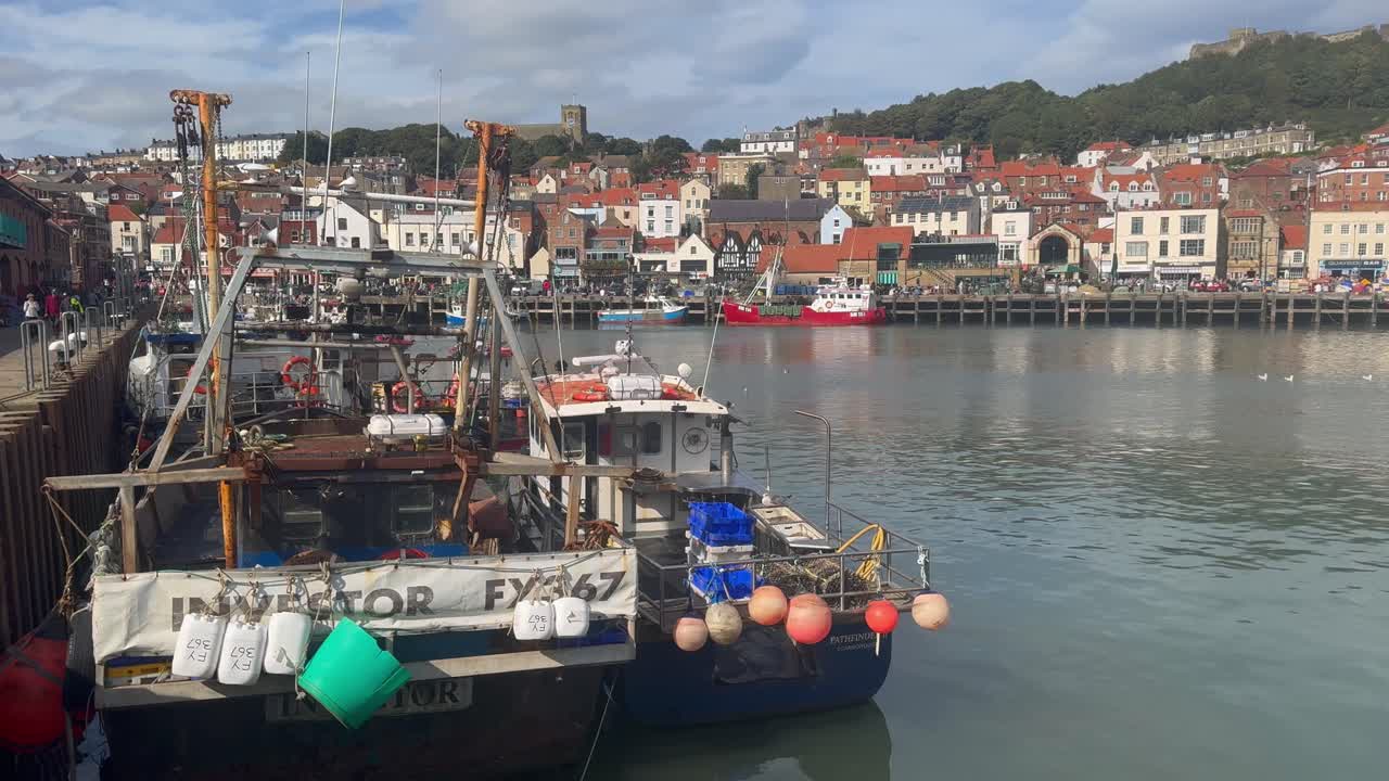 Fishing boats rest at Scarborough Harbour, highlighting a vibrant fishing community with beautiful coastal scenery.