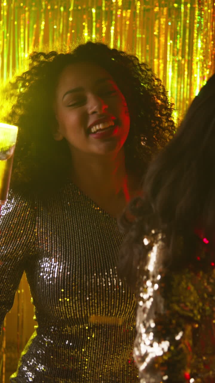Vertical Video Of Two Women In Nightclub Or Bar Dancing Drinking Alcohol With Sparkling Lights And Confetti In Background