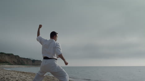 karate fighter training strength on beach. man standing in fighting position.