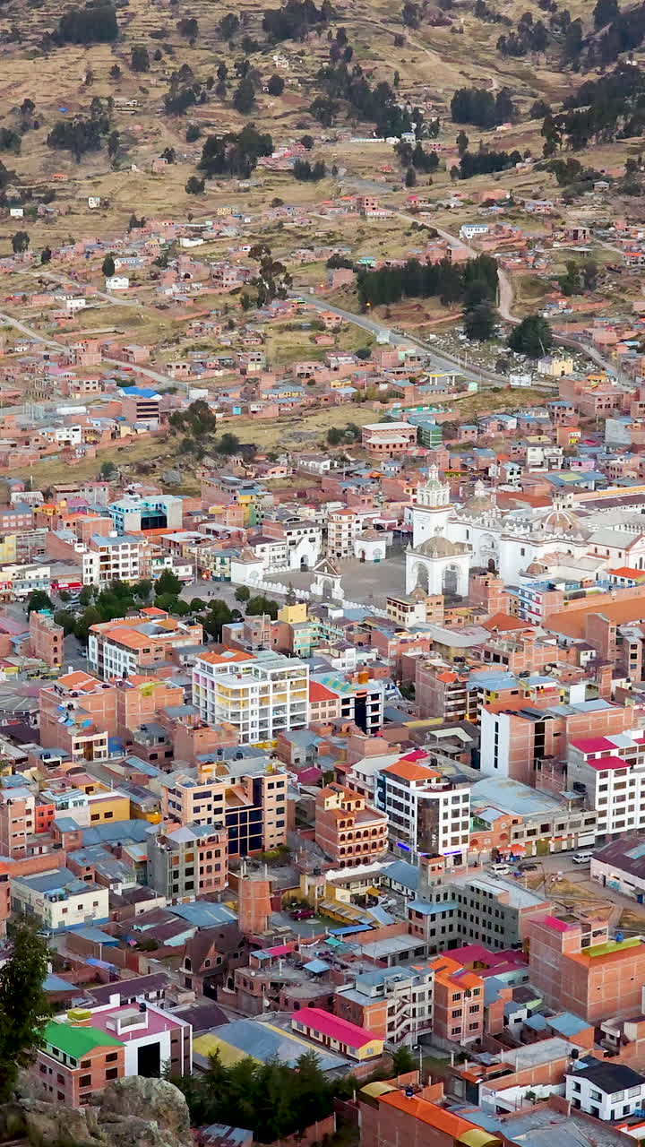 Experience a breathtaking vertical aerial shot of Copacabana, Bolivia, at dusk, as seen from the top of Cerro Calvario