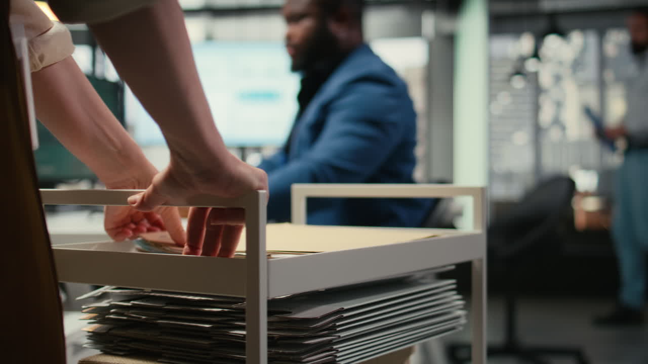 Close up of office secretary pushes trolley filled with paperwork and documents