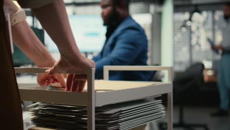 close up of office secretary pushes trolley filled with paperwork and documents