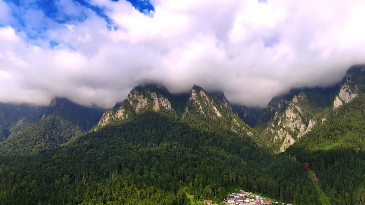 Misty peaks of Bucegi Mountains covered by clouds. Panoramic shot of the Bucegi Mountains peaks shrouded in clouds