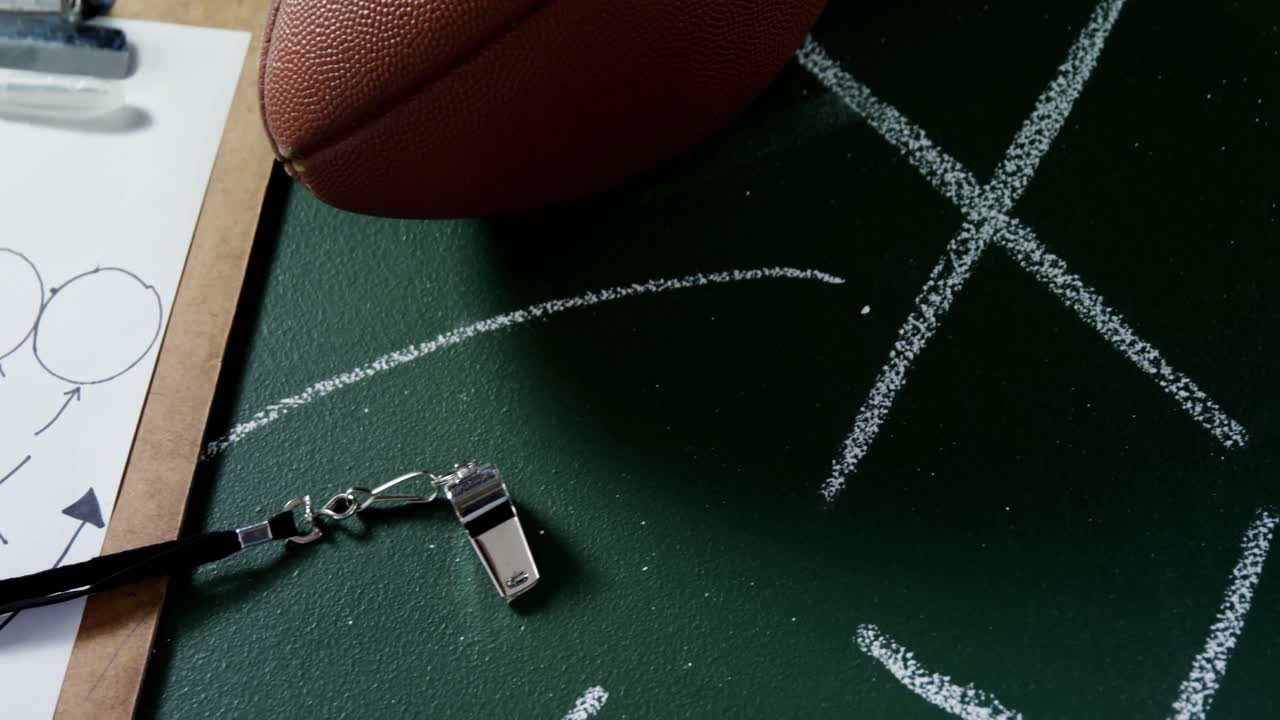 American football, clipboard and referee whistle on green board 4k
