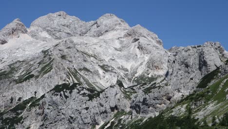 Vodnikov-dom-na-Velem-polu-tourist-cottage-in-Slovenian-Julian-Alps,-zooming-shot-on-Vernar-peak