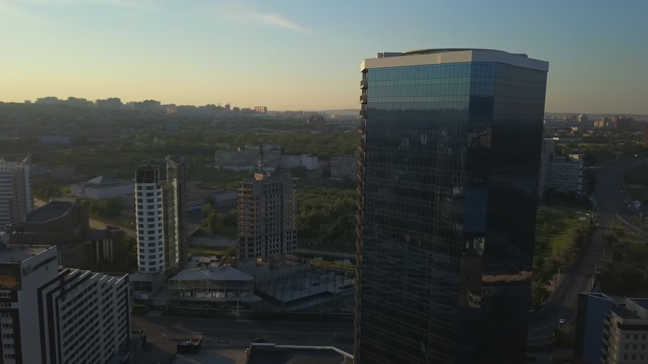 округлый вид современного делового офиса, отражающего городской пейзаж красноярска.