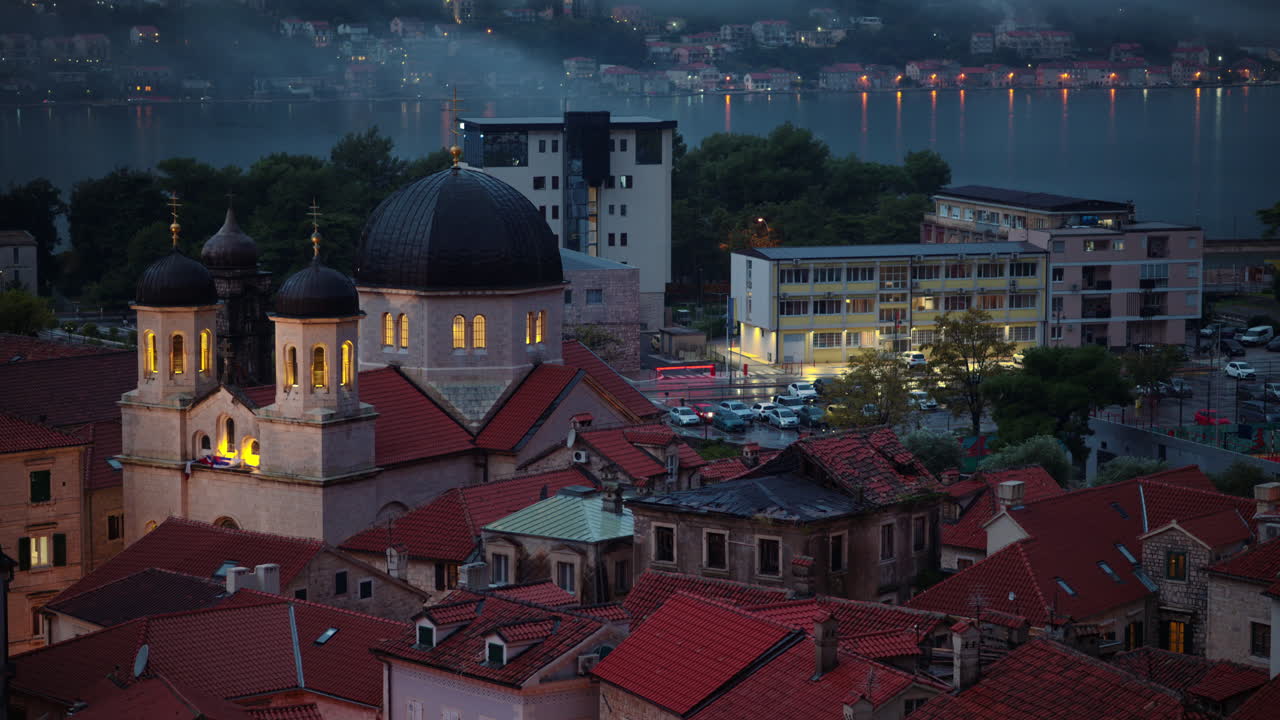 Cúpulas de igrejas ortodoxas iluminando a baía cênica com neblina cobrindo as montanhas ao anoitecer. Cidade Velha de Kotor, Montenegro