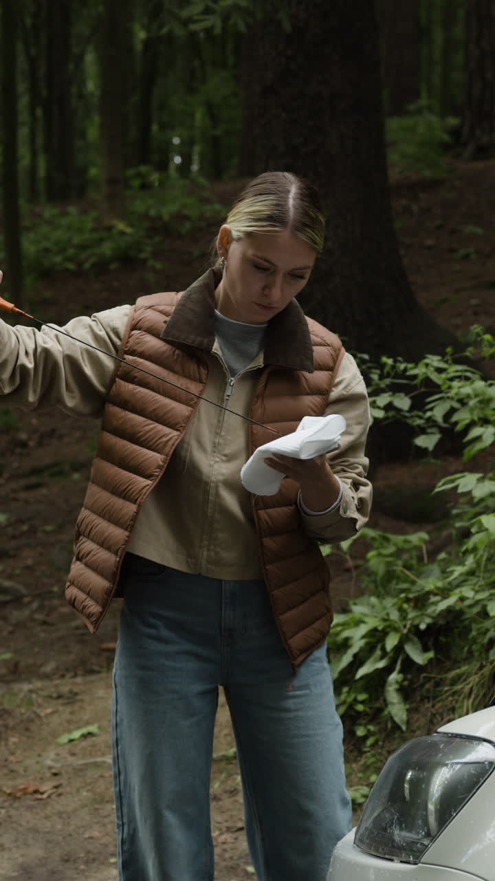 Woman checking car oil in forest